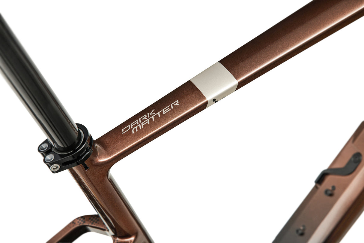 Top tube branding of Argon 18 Dark Matter Force XPLR AXS Gravel Bike with 'Dark Matter' logo and sleek bronze finish.