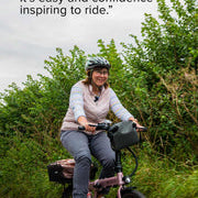 Woman riding rose gold estarli E20.7 Comfort Hybrid E-Bike with quote praising its ease and confidence-inspiring ride quality.