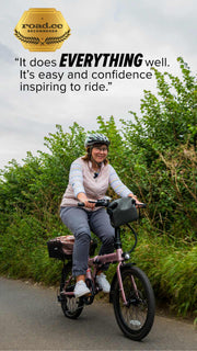 Woman riding rose gold estarli E20.7 Comfort Hybrid E-Bike with quote praising its ease and confidence-inspiring ride quality.
