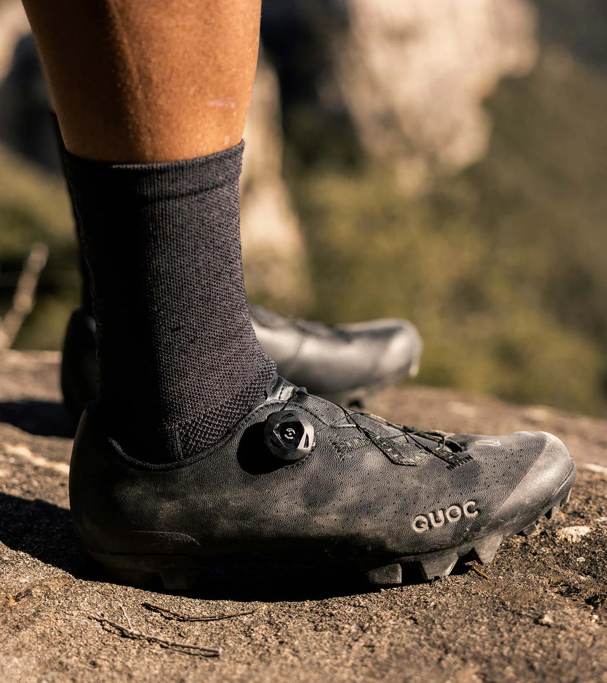 QUOC Escape Off-Road Shoe in black worn outdoors, showcasing durability and grip for off-road cycling adventures.