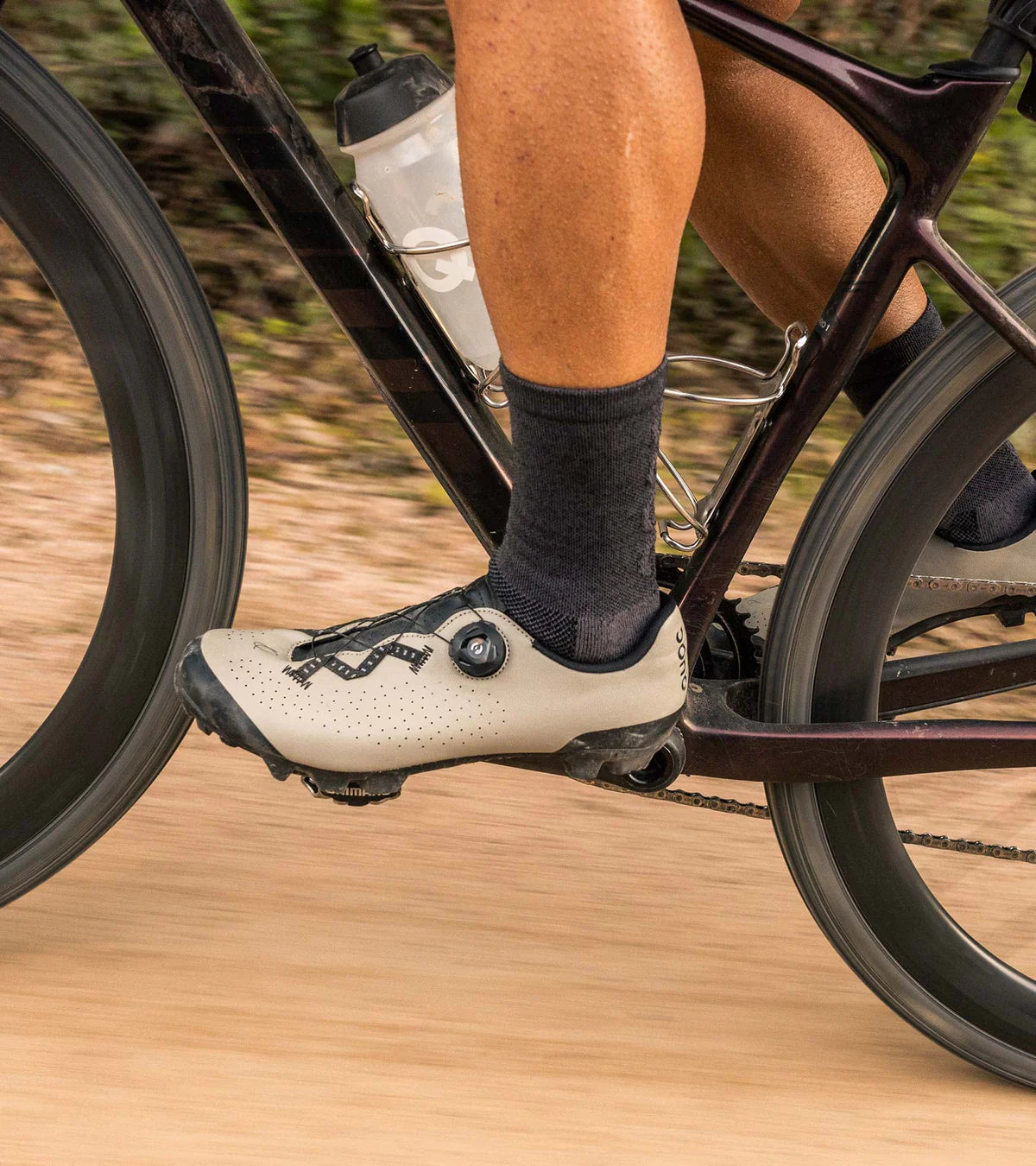 QUOC Escape Off-Road Shoe in sand color worn while cycling, demonstrating pedal efficiency and off-road grip.