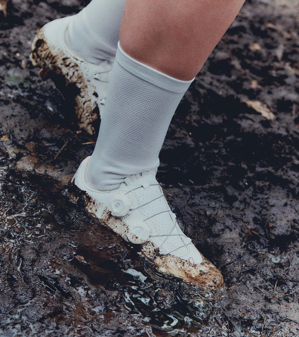 QUOC Gran Tourer XC Off-Road Shoes in white shown in muddy terrain, emphasizing their durability and grip in extreme off-road conditions.