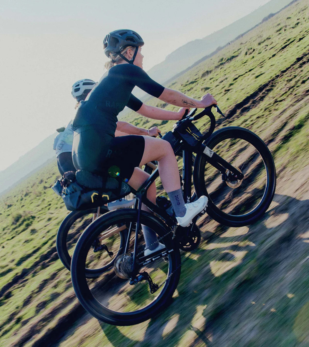 Two cyclists wearing QUOC Gran Tourer XC Off-Road Shoes riding gravel bikes on a dirt trail, highlighting the shoes' adventure-ready design.