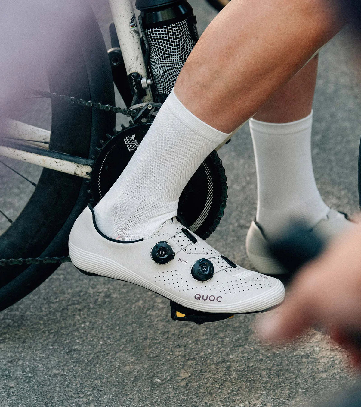Cyclist wearing QUOC M3 Sport Road Shoes clipped into pedals, emphasizing secure fit and road cycling functionality.