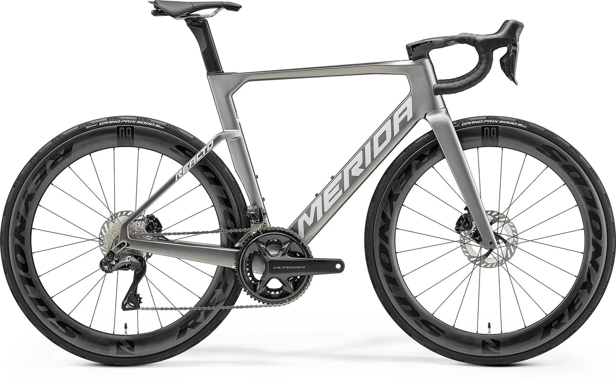 Merida Reacto 8000 Road Bike in matte silver finish featuring aero carbon frame, integrated cockpit, and high-performance disc brakes for racing efficiency.