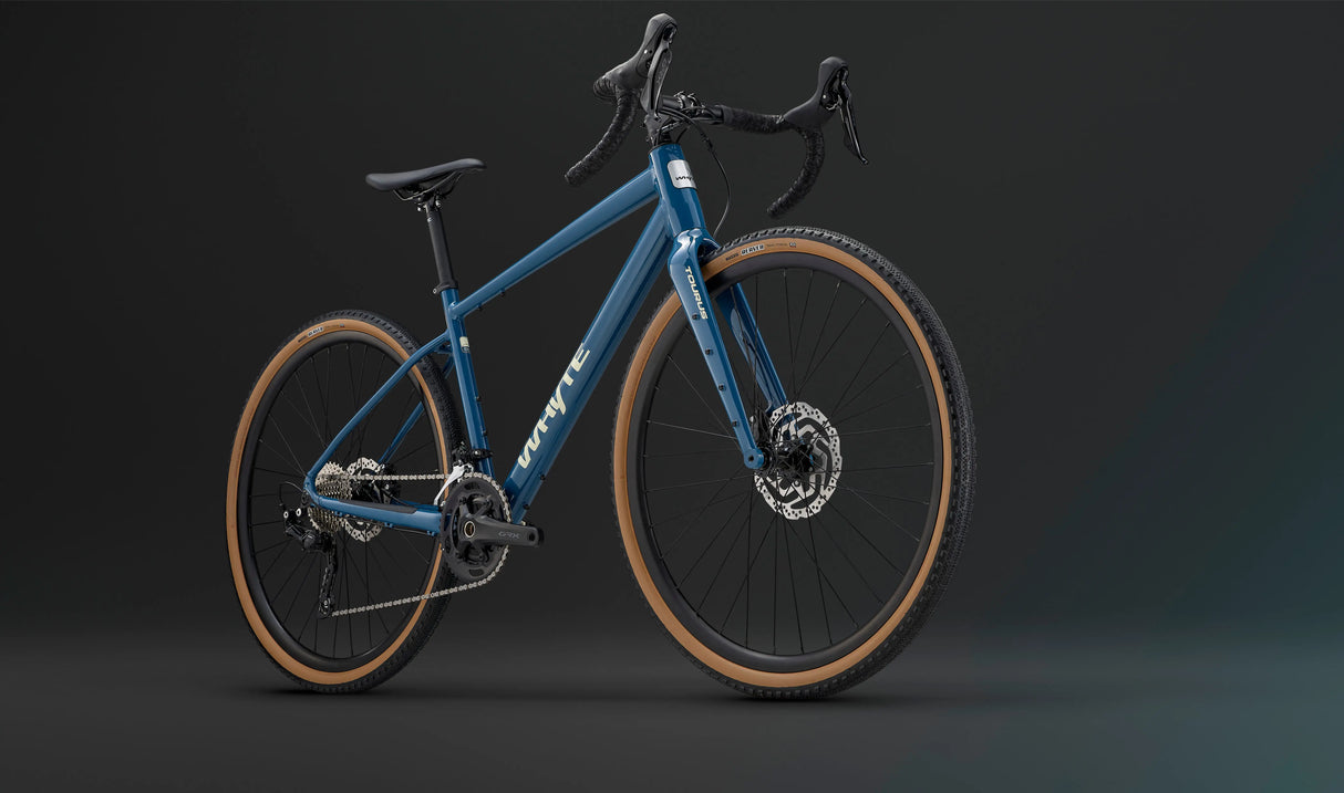 Front-side view of the blue Whyte Tourus Gravel Bike highlighting its rugged tires, disc brakes, and ergonomic drop bar design.