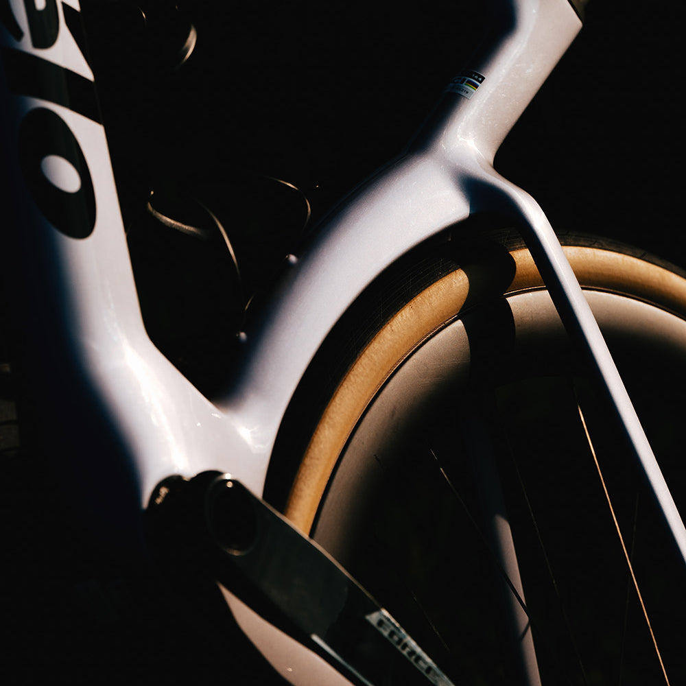 Artistic close-up of white Cervelo Aspero-5 SRAM Force AXS 1 Gravel Bike's rear triangle and tire, highlighting aerodynamic contours.