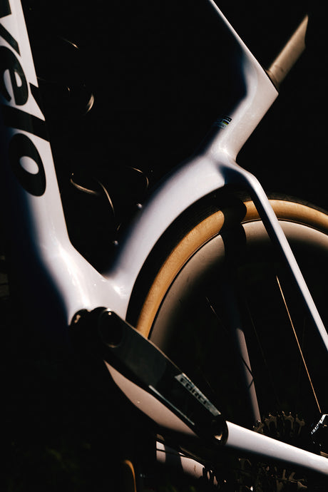 Artistic close-up of white Cervelo Aspero-5 SRAM Force AXS 1 Gravel Bike's rear triangle and tire, highlighting aerodynamic contours.