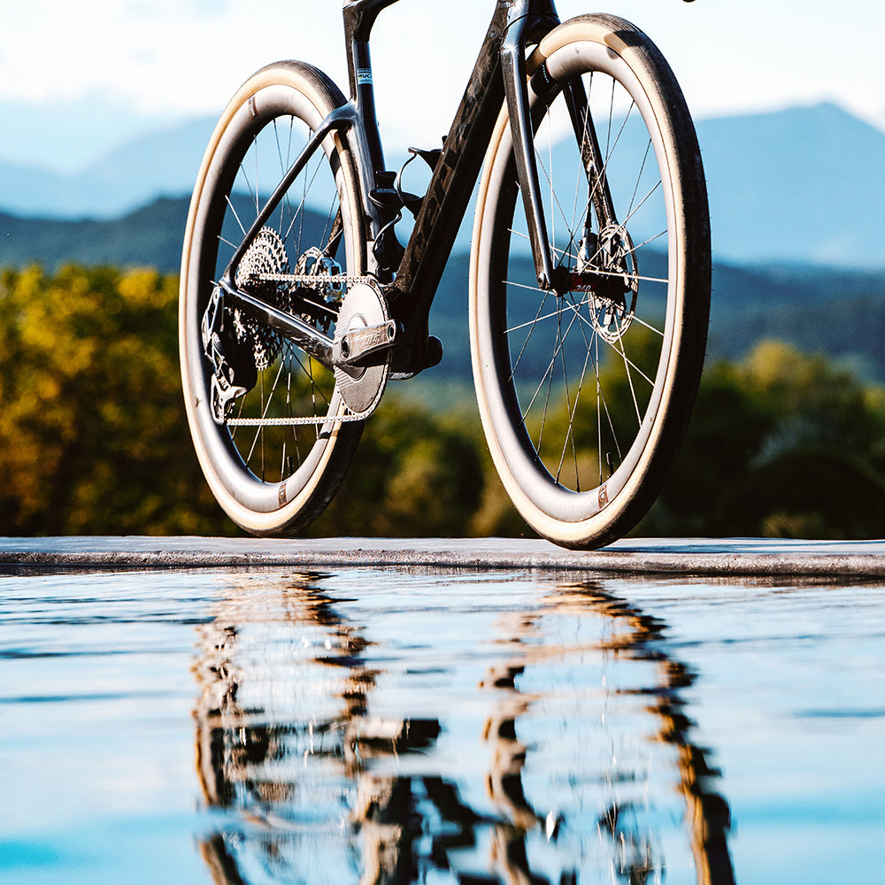 Cervelo Aspero-5 SRAM Force AXS 1 Gravel Bike reflected in water with mountain backdrop, emphasizing its premium design and adventure appeal.