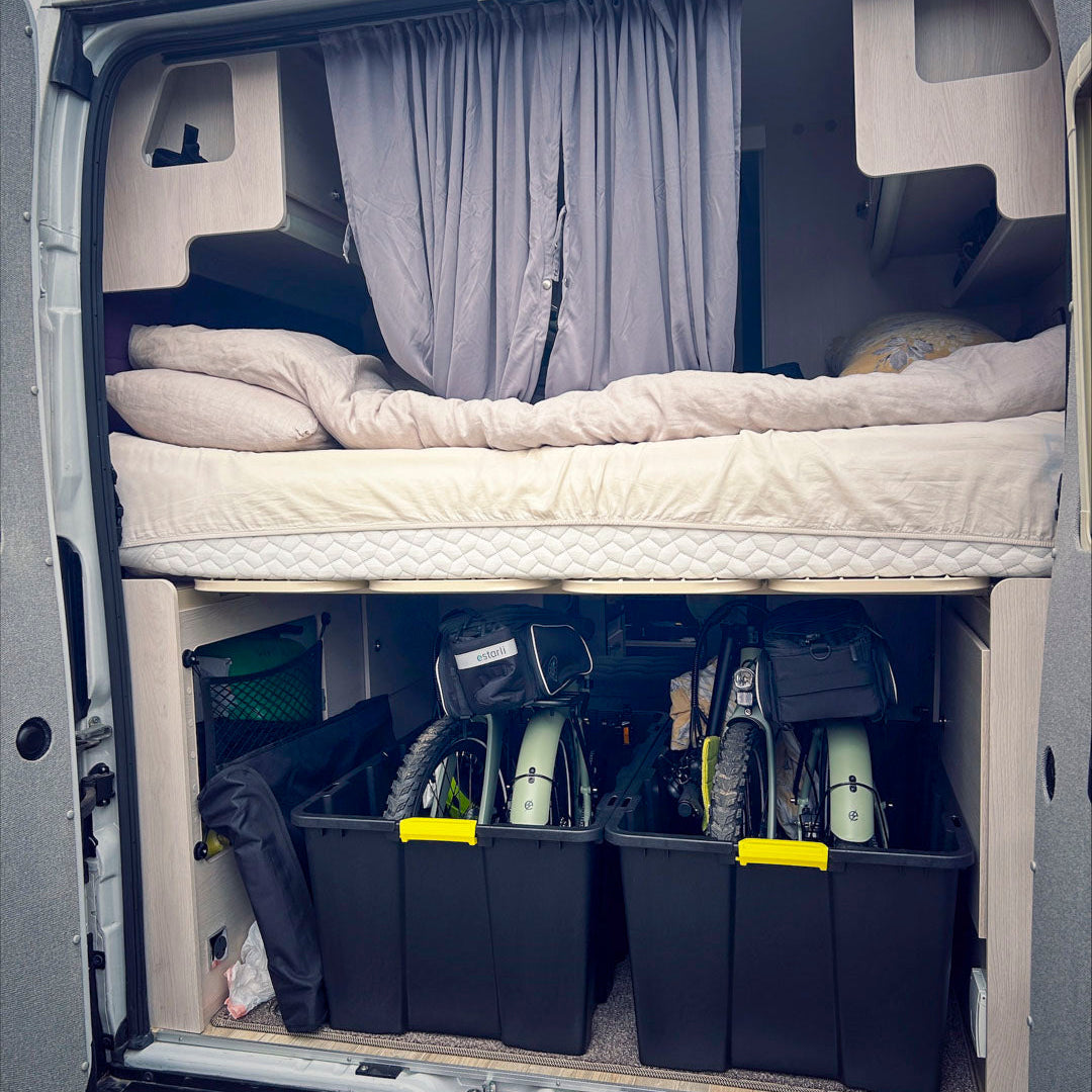 Folded estarli E20.8 Play Hybrid E-Bikes neatly packed in a camper van storage compartment, ideal for mobile lifestyles.