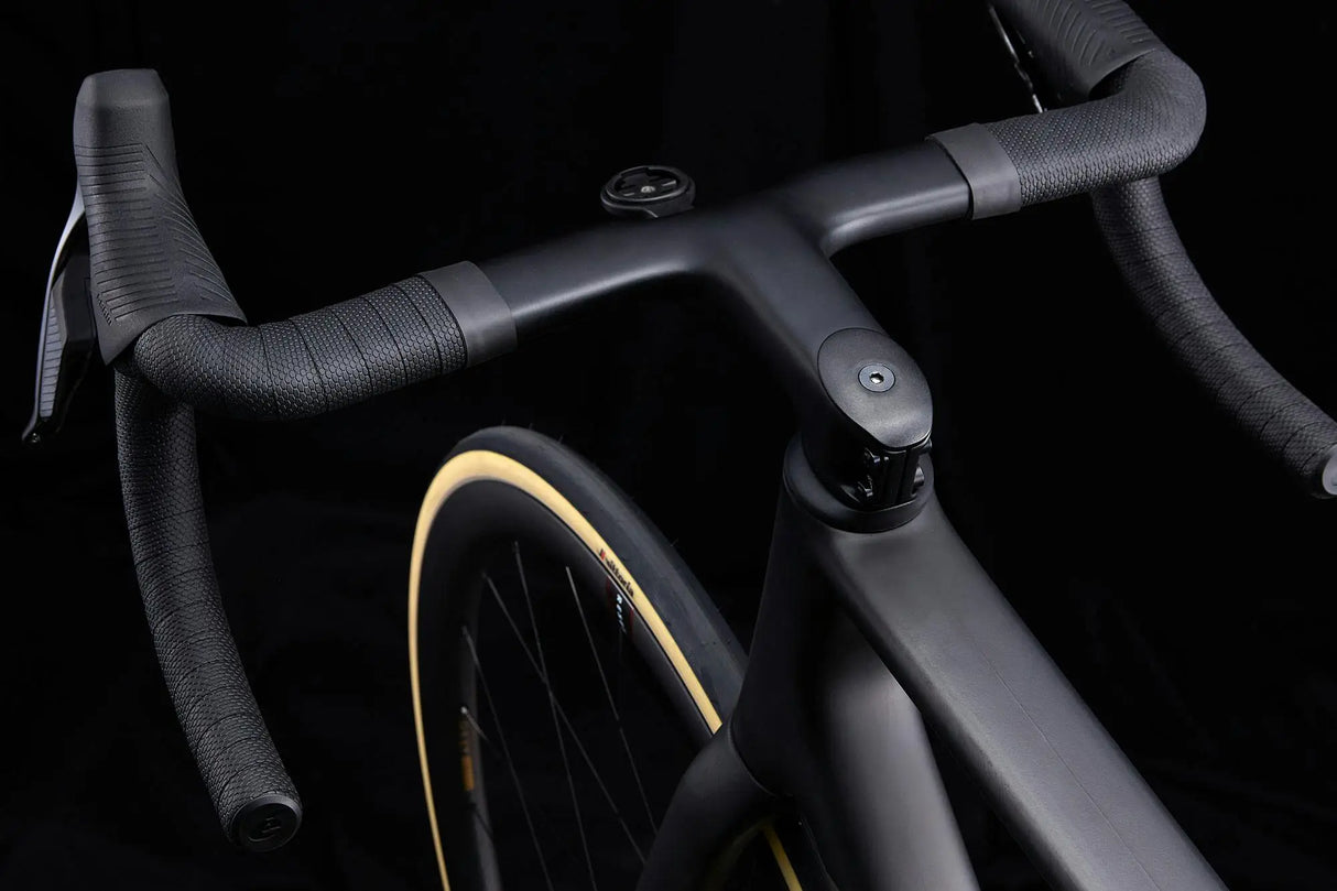 Close-up of a bicycle handlebar and front wheel on a black background