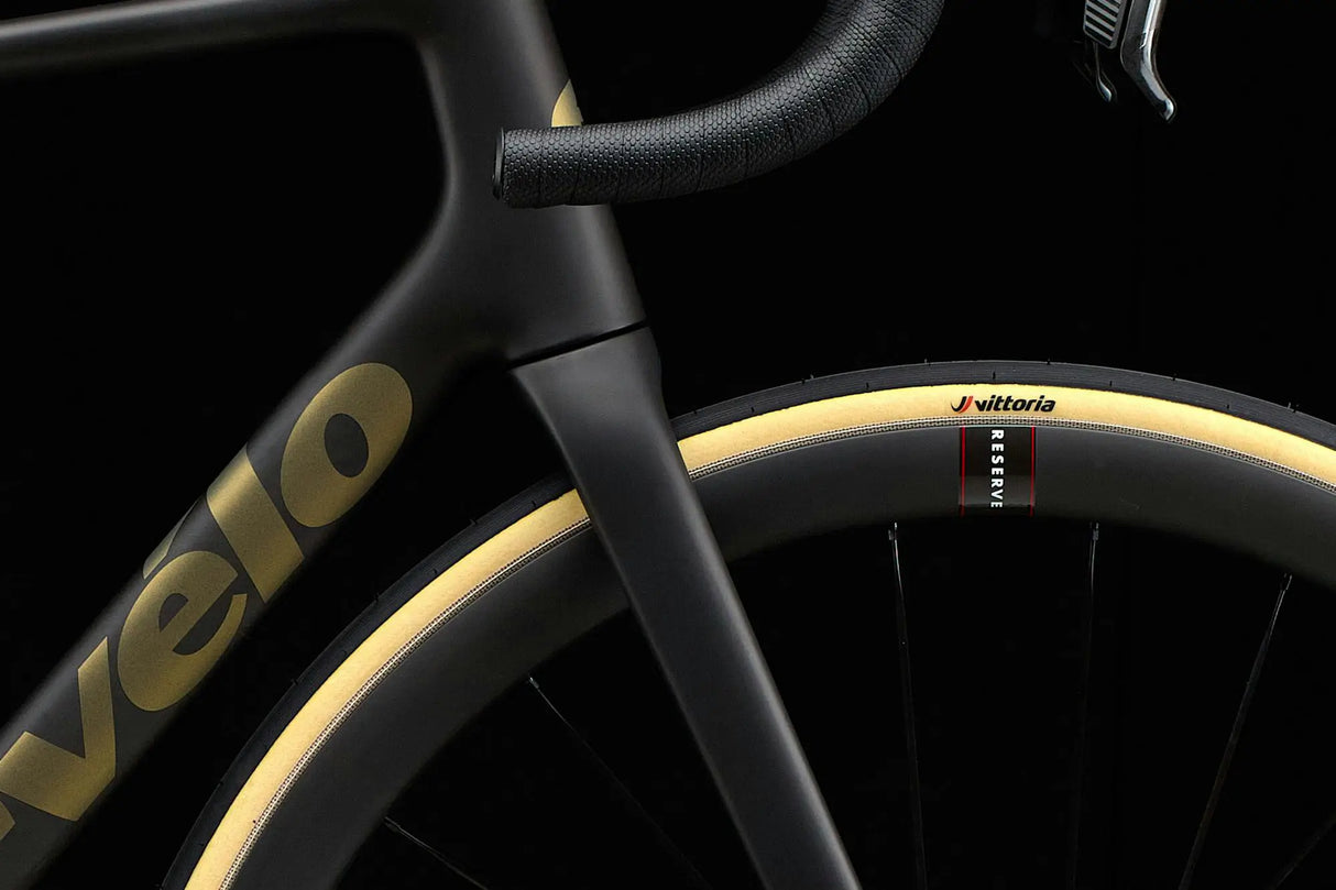 Close-up of a bicycle with 'velo' branding on the frame against a black background