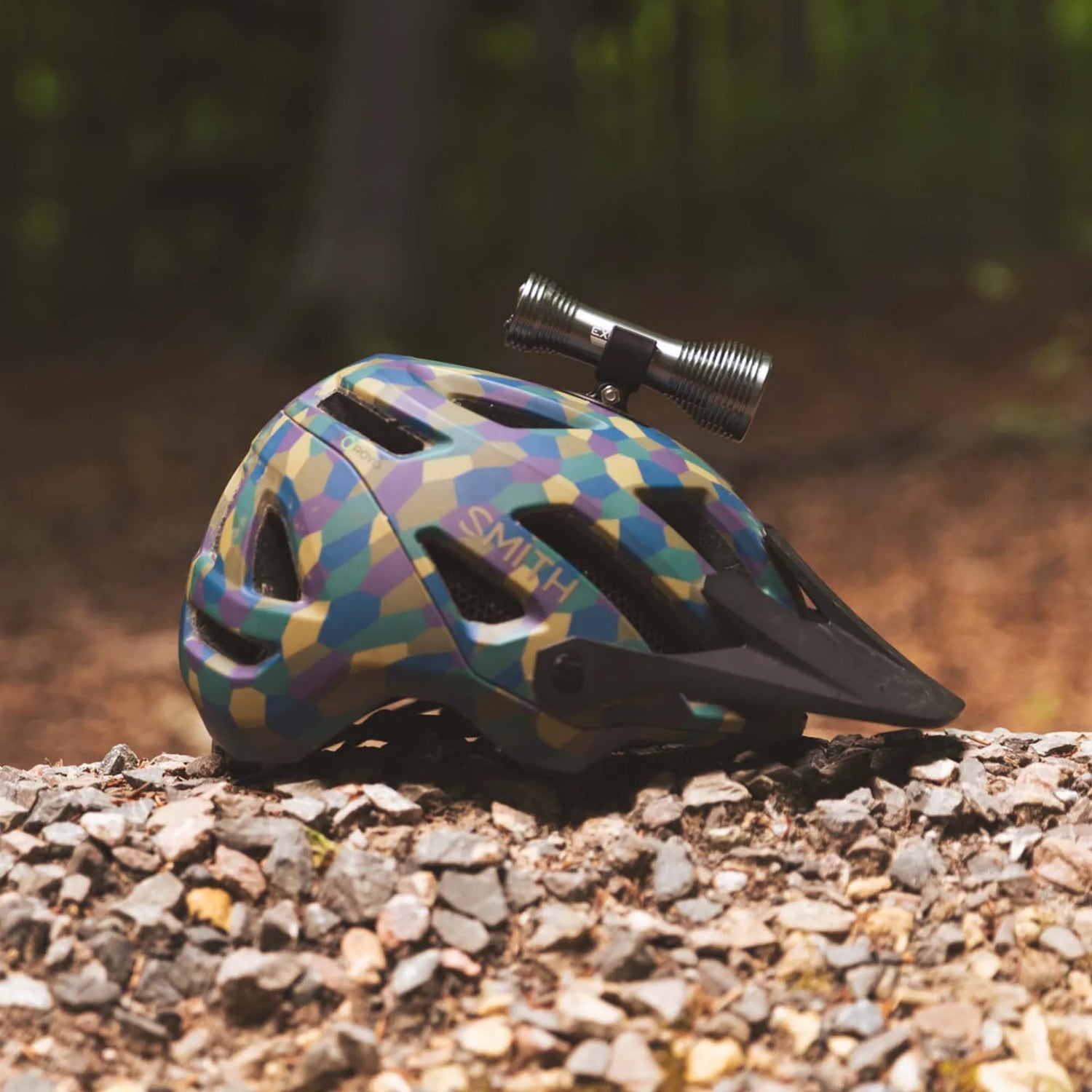 Colorful helmet with a light attached on a gravel surface