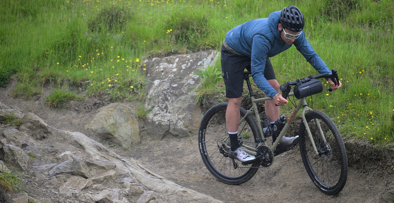 Rider navigating rocky terrain on the 2025 Genesis Croix De Fer 30 Gravel Bike, demonstrating its performance on technical trails.