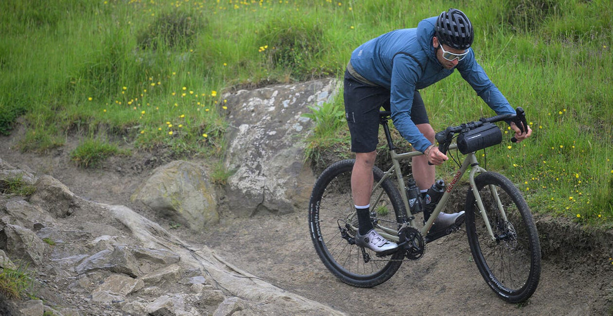 Rider navigating rocky terrain on the 2025 Genesis Croix De Fer 30 Gravel Bike, demonstrating its performance on technical trails.