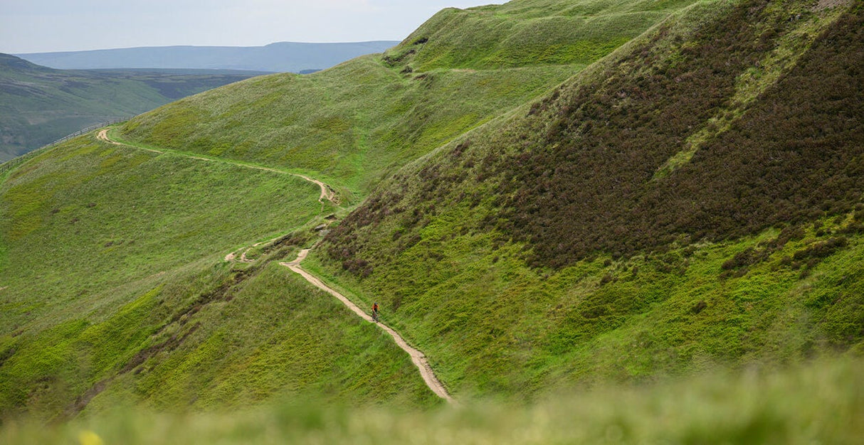 Winding gravel trail through green hills, ideal terrain for the 2025 Genesis Croix De Fer 30 Gravel Bike's adventure capabilities.