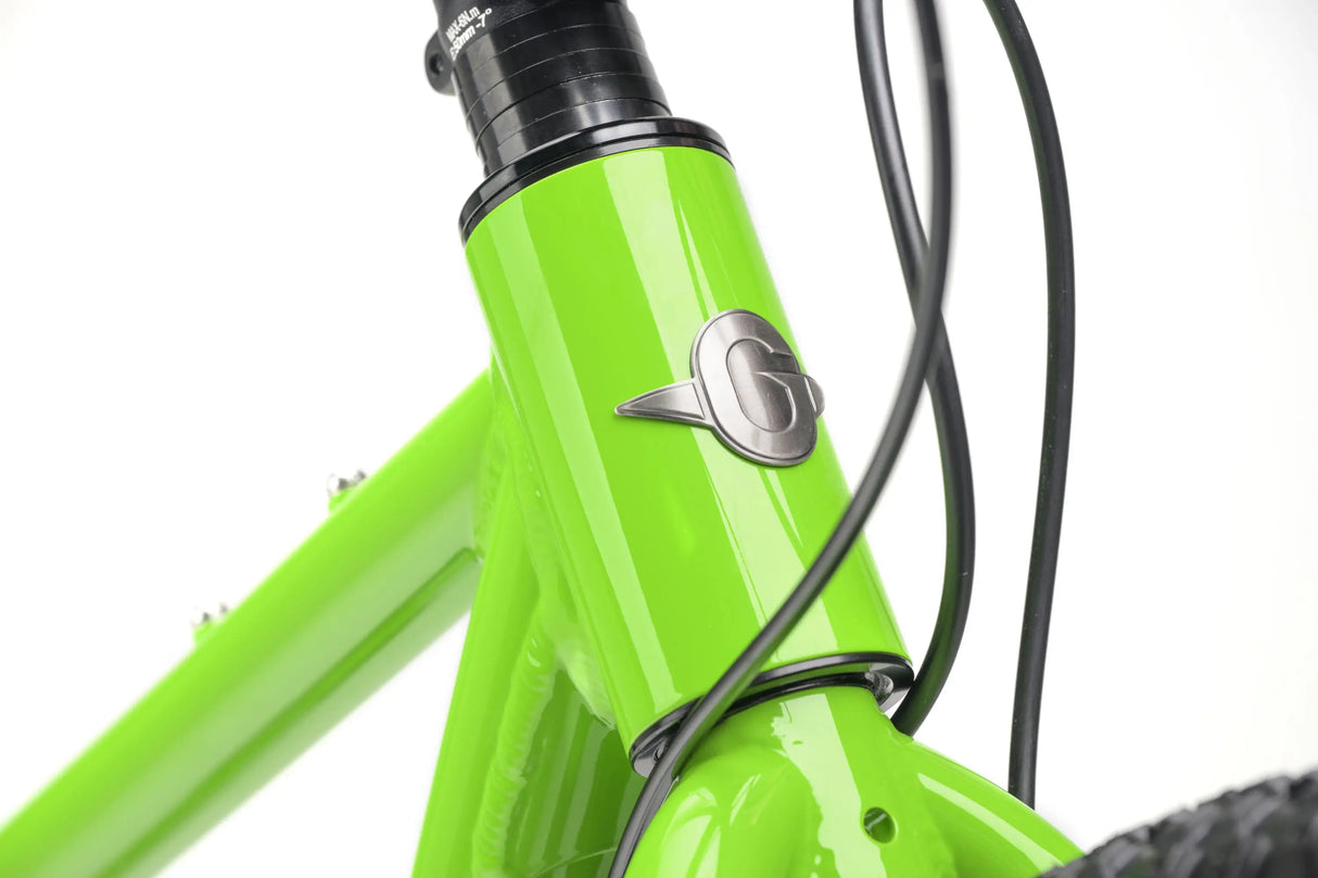 Close-up of bright green kids gravel bike frame with gray logo and black cables.