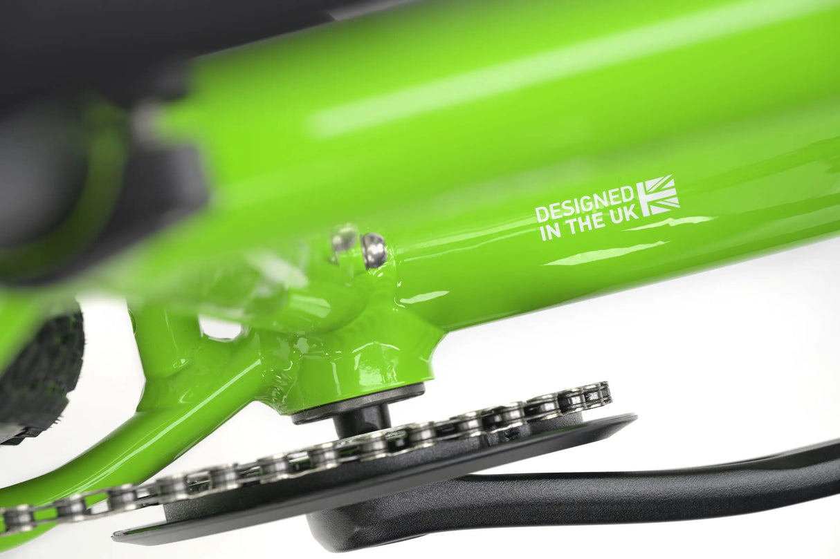 Bright green frame detail of Genesis CDA JNR kids gravel bike with chainring and "Designed in the UK" text.