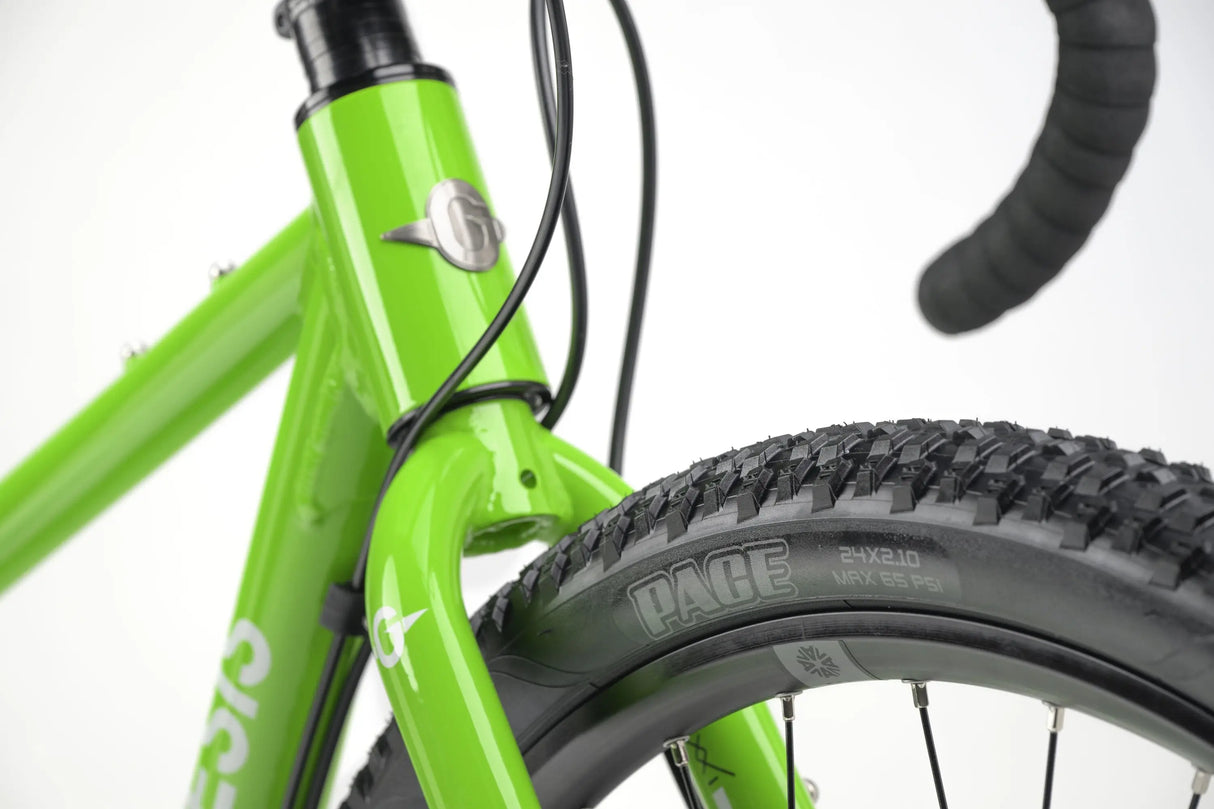 Bright green kids gravel bike frame with thick treaded tire and black drop handlebars.