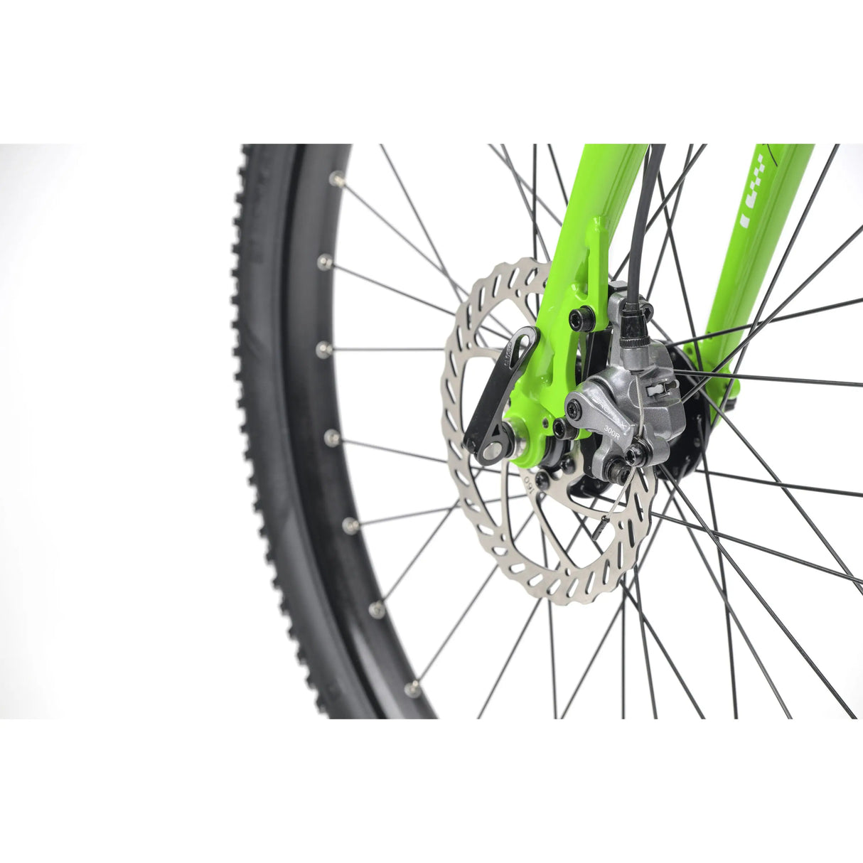 Close-up of green kids gravel bike front wheel with disc brake and knobby tire on white background.