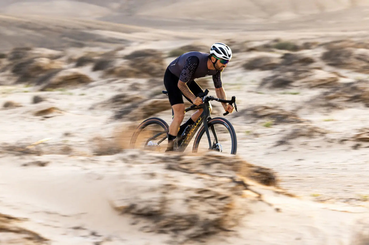 Cyclist riding on a gravel road in a desert landscape