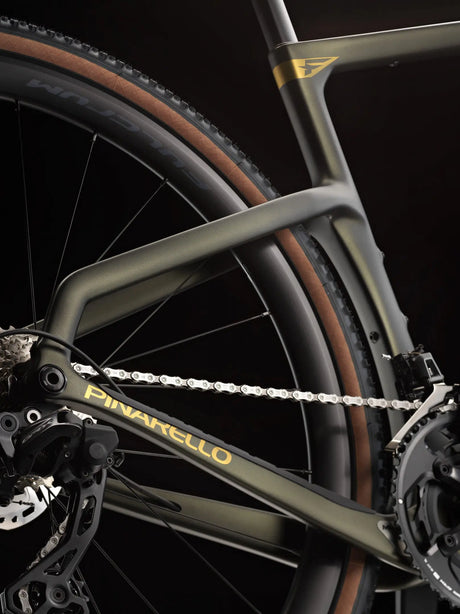 Close-up of a bicycle chain and gear system with 'Pinarello' branding on a dark background