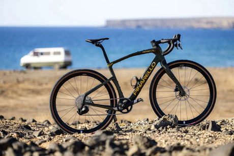 Pinarello bicycle on a rocky beach with ocean and van in the background