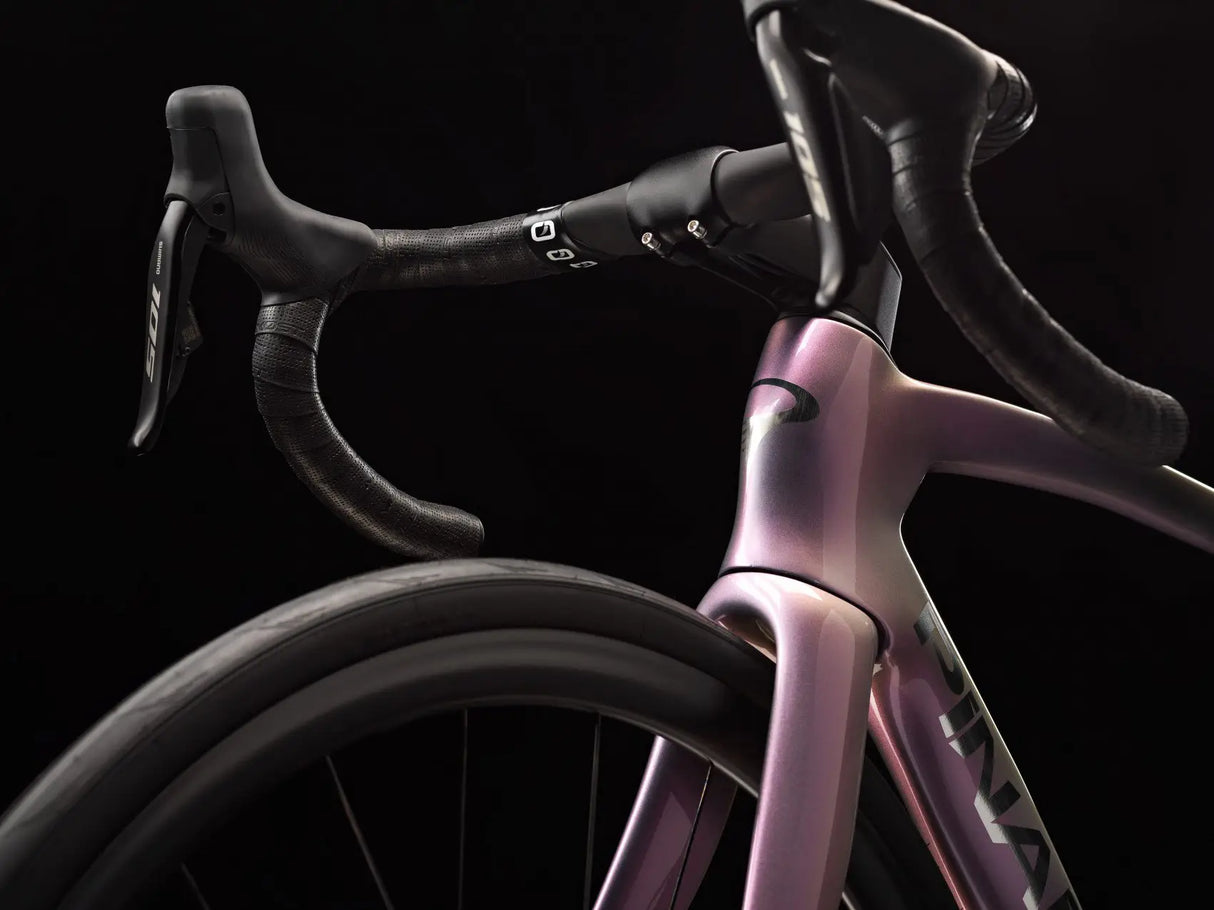 Close-up of a pink bicycle frame with black handlebars on a black background