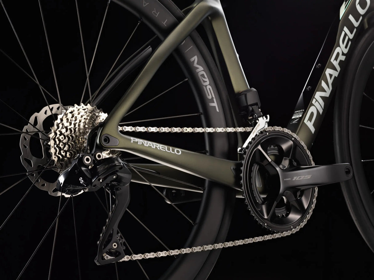 Close-up of a bicycle chain and gear system with 'Pinarello' branding on a black background.
