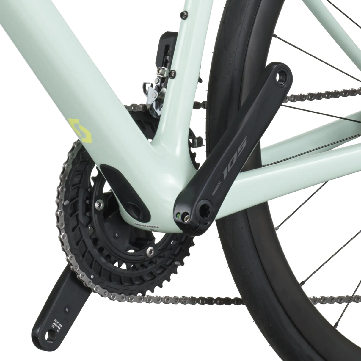 Close-up of a bicycle chain and gear system on a light green frame.