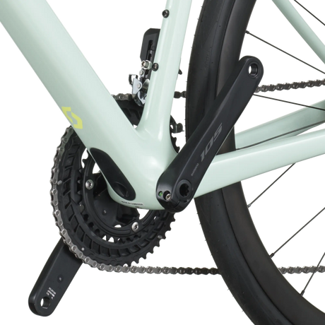 Close-up of a bicycle chain and gear system on a light green frame.