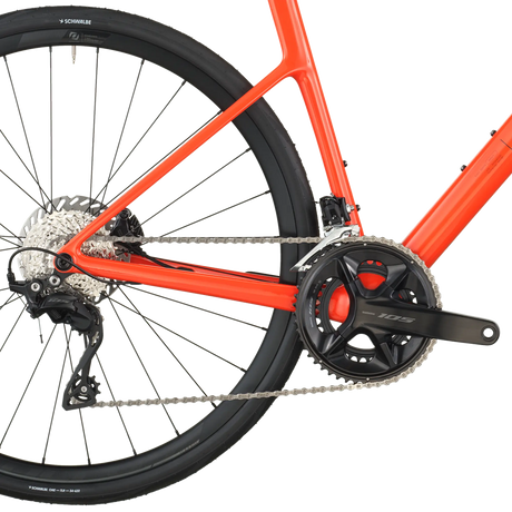 Close-up of a red bicycle with chain and gear system on a white background