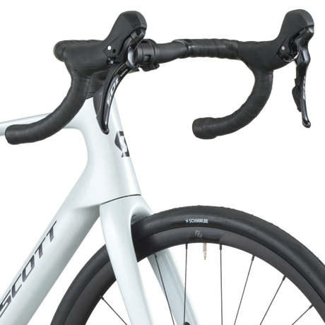 Close-up of a white bicycle with black handlebars on a white background