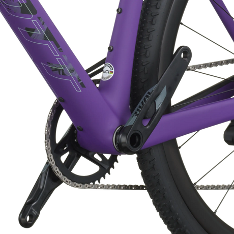 Close-up of a purple bicycle frame with chain and wheel on a white background