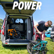 Man folding estarli E20.7 Comfort Hybrid E-Bike beside camper van, emphasizing power, comfort, and portability for outdoor adventures.