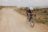 Rider descending a dusty gravel road on an Argon 18 Anti Matter, background blurred