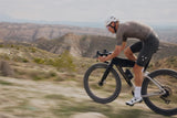 Rider cornering on an Argon 18 Anti Matter gravel bike with mountains behind