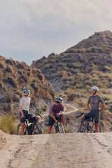 Three riders on Argon 18 Anti Matter gravel bikes on a track below rocky hills