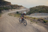 Rider on an Argon 18 Anti Matter gravel bike on a winding gravel road through dry hills
