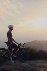 Rider standing with an Argon 18 Anti Matter gravel bike, silhouetted against a hazy sunset