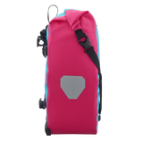 Cyber pink waterproof pannier bag with black strap and reflective gray patch on side.