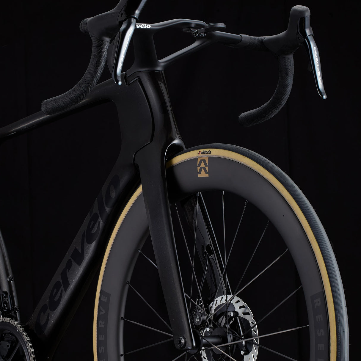 Close-up of black Cervélo S5 Dura-Ace Di2 front fork and Vittoria tire on Reserve wheel, emphasizing aerodynamic fork design and disc brake integration.