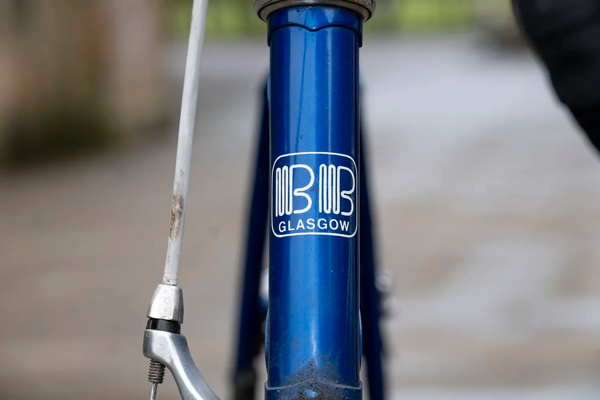 Front badge of a blue Billy Bilsland bike frame with 'BB Glasgow' logo, tying into the 45th Anniversary Jersey theme.