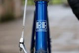 Front badge of a blue Billy Bilsland bike frame with 'BB Glasgow' logo, tying into the 45th Anniversary Jersey theme.