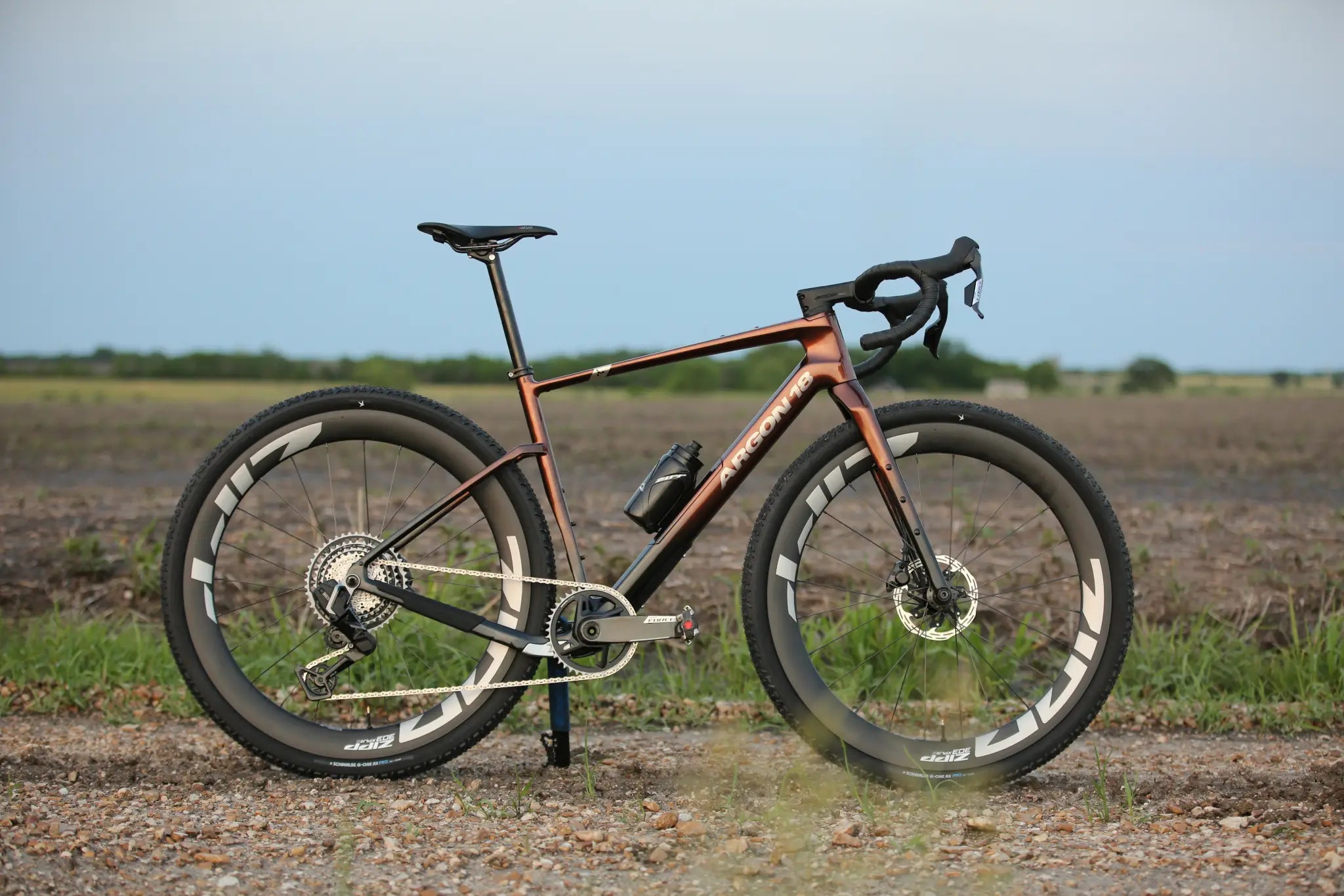 Argon 18 Dark Matter Rival XPLR AXS Gravel Bike with deep-section carbon wheels on a gravel path, built for high-speed adventure riding.