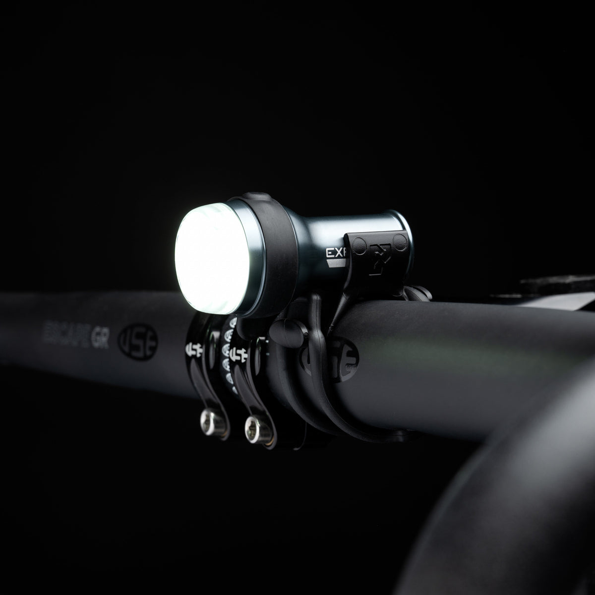 Exposure Trace Mk4 front light switched on, clamped to a handlebar in the dark