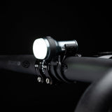 Exposure Trace Mk4 front light switched on, clamped to a handlebar in the dark