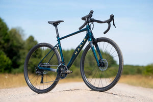 Marin Gestalt 1 gravel bike side-on on a gravel track, with trees and open ground behind