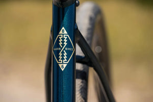Gold Marin Bikes diamond badge on the metallic teal frame of the Gestalt 1