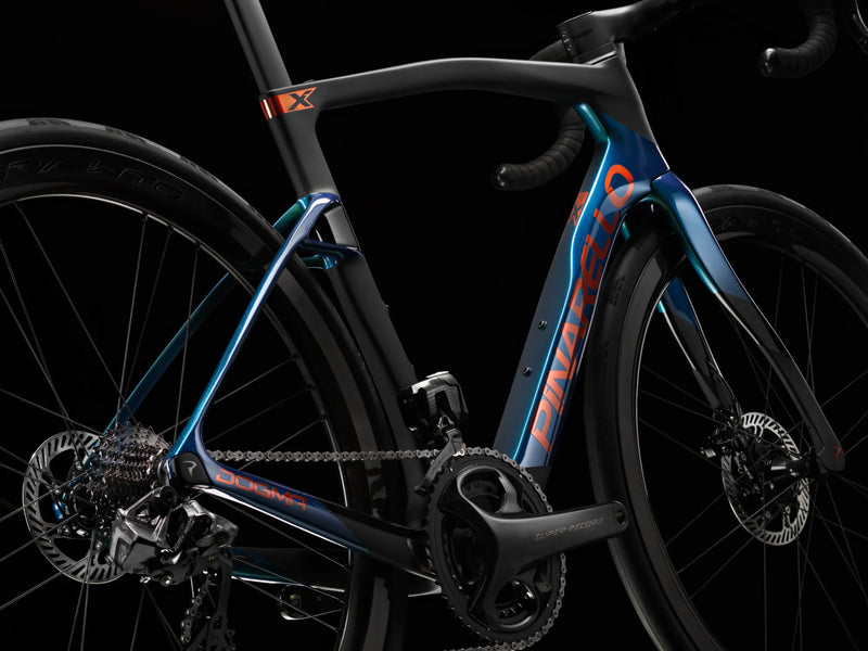 Close-up of the down tube and fork of the teal Pinarello Dogma X against a dark background